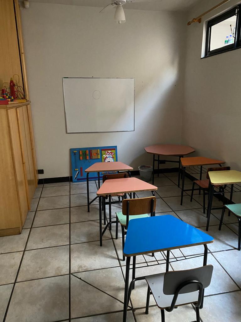 Sala de aula com mesinhas coloridas e lousa