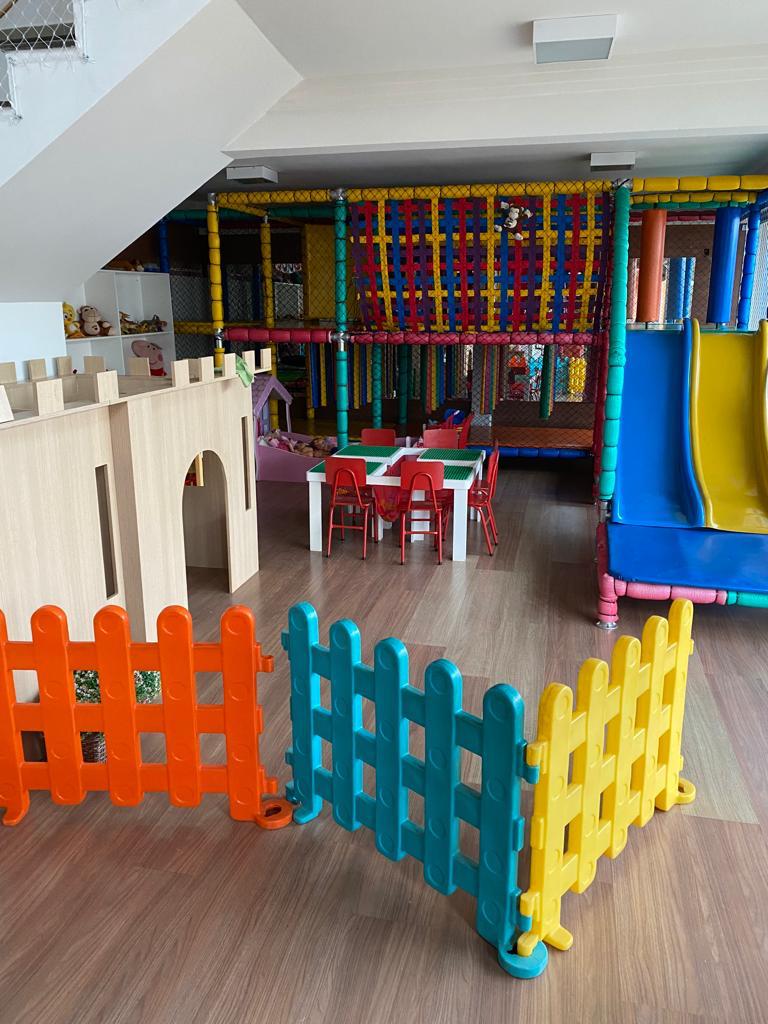 Brinquedoteca ampla com castelo, escorregador e mesinhas