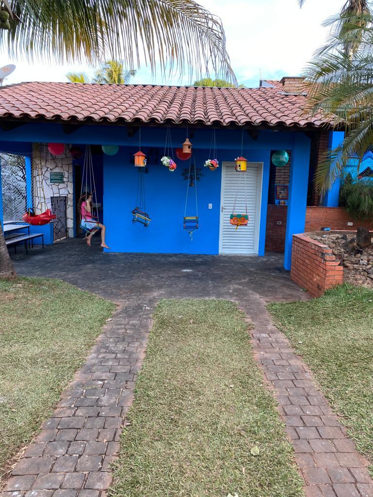 Fachada azul com balanços coloridos e jardim